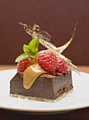 A piece of chocolate tart with raspberries and caramel