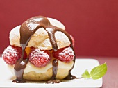 Profiterole with chocolate sauce, vanilla cream raspberries