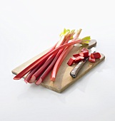 Rhubarb, partly sliced, on chopping board