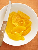 Orange segments in dish with knife