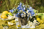 Vase of delphinium, yarrow and feverfew out of doors