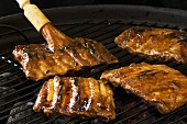 Brushing pork ribs on a barbecue with marinade