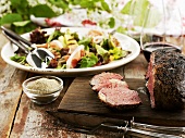 Roast beef, partly carved, salad in background