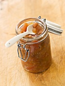 Apple chutney with raisins in preserving jar with spoon