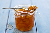 Apricot jam with almonds in jar and on spoon