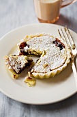 Berry tart with icing sugar, a piece cut