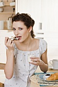 Young woman eating yoghurt for breakfast