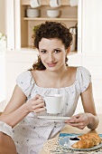 Young woman drinking coffee at breakfast table
