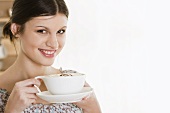 Junge Frau trinkt Kaffee mit Milchschaum