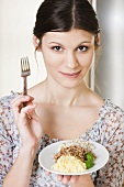 Young woman holding a plate of cooked grains