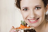 Young woman eating crispbread with salmon