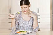 Junge Frau isst Fisch mit Couscous und Gemüse