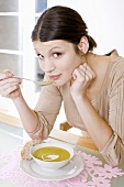 Young woman eating cream of pea soup