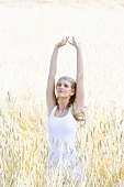 Blond woman, stretching, standing in a cornfield