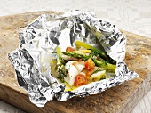 Fish fillet with asparagus and tomatoes in aluminium foil