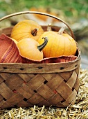 Small pumpkins in a woven basket on straw