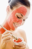 Young woman with red facial mask