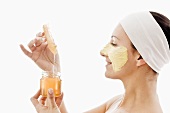 Woman with honey facial mask, jar of honey and honeycomb