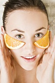 Junge Frau mit Orangenscheiben im Gesicht