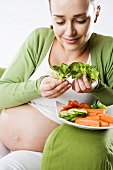 Schwangere Frau isst frisches Gemüse