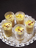 Saffron yoghurt ice cream in several glasses on tray (India)