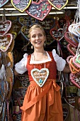 Woman in dirndl by stall selling Lebkuchen hearts (Oktoberfest)