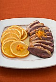 Sliced duck breast with orange slices