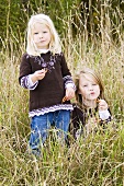 Two girls with salted pretzels in long grass