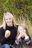 Mutter und Tochter essen Apfel auf der Wiese