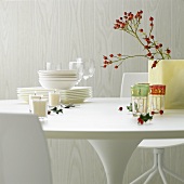 White tableware, glasses, candles, rose hips & holly on table