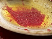 Raspberry vinaigrette on silver spoon (close-up)