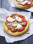 Minipizza mit Tomaten, Mozzarella und Pinienkernen