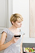 Young woman with a glass of red wine and salad