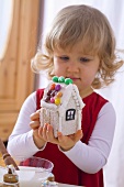 Kleines Mädchen mit verziert ein Lebkuchenhaus