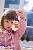 Girl holding salt dough snowman (tree ornament)