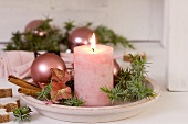 Candle, juniper, Christmas baubles & hydrangea flowers on plate