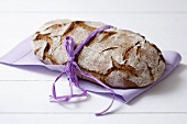 Wholemeal bread with ribbon on purple fabric napkin