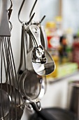 Various kitchen tools hanging on hooks in a kitchen