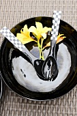 Black plate with cutlery and yellow flowers