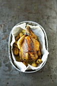 Guinea fowl stuffed with morels, potatoes in baking dish