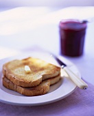 Two slices of toast with butter and strawberry jam