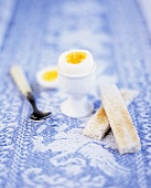 A boiled egg with the top removed and toast soldiers