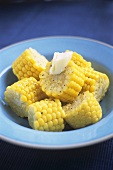 Chunks of cooked corn on the cob with butter and pepper