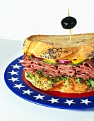 Pastrami-Sandwich mit Mohnbrot auf Teller mit US-Farben