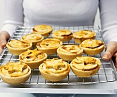 Woman holding mince pies on baking rack (UK)