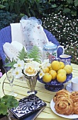 Flowers, yellow plums and raisin buns on garden table