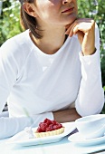 Young woman with raspberry tart in the open air