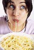 Young woman with a strand of spaghetti in her mouth
