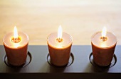 Three burning candles in shallow candle holder