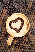 Cappuccino mit Herzmuster im Milchschaum und Kaffeebohnen